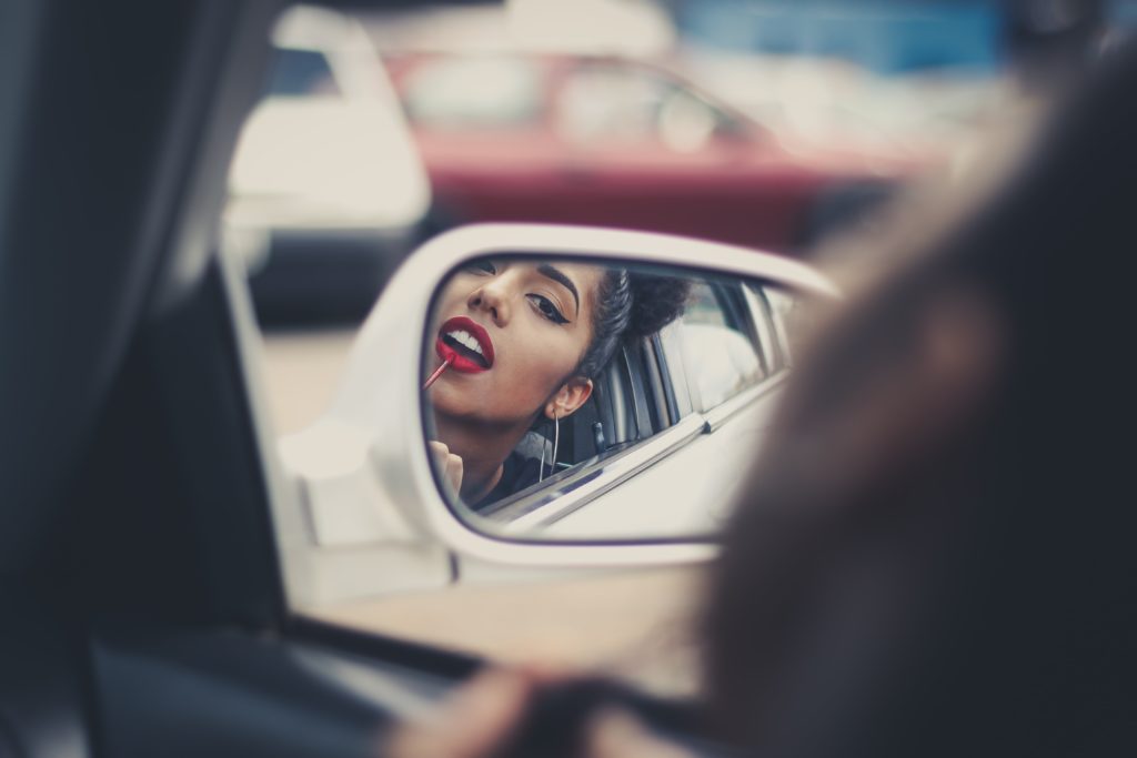 Girl putting on lipstick in car